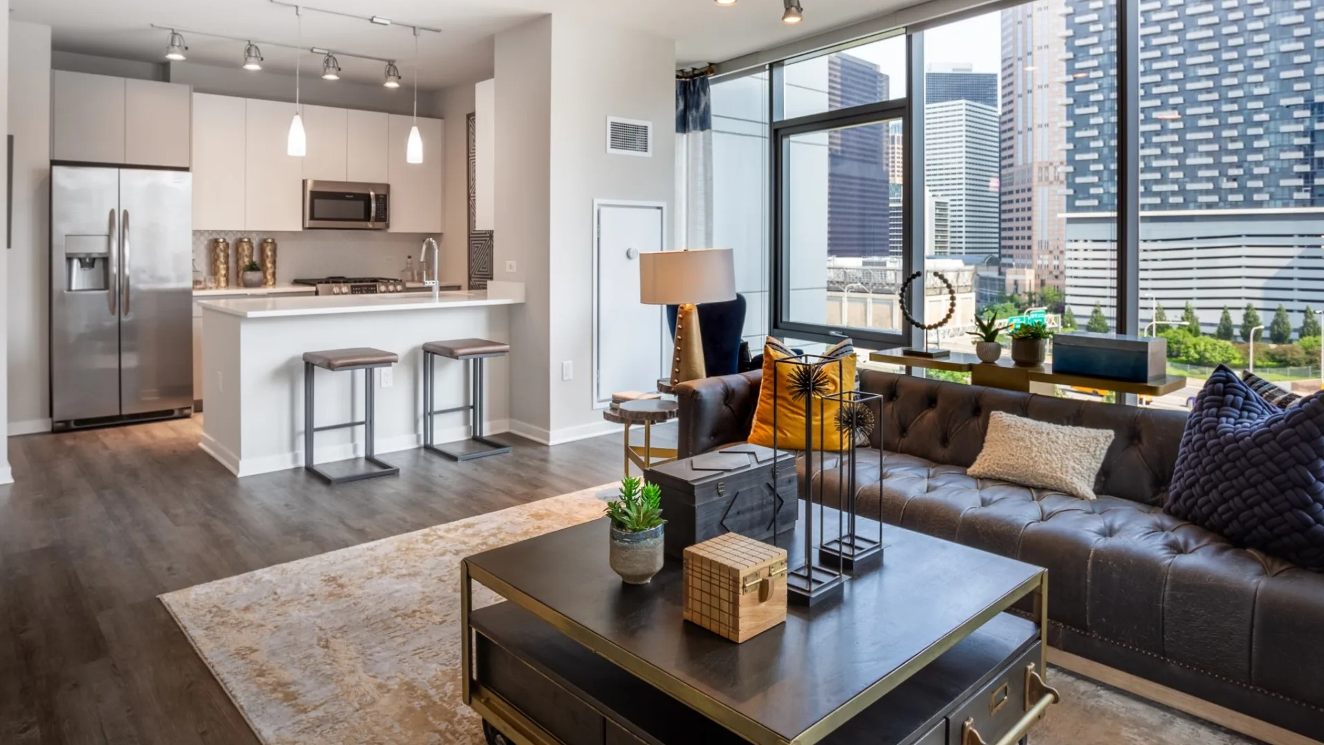 Modern open-concept kitchen and living room at The Grand Central Apartments in Chicago, featuring stainless steel appliances and city views