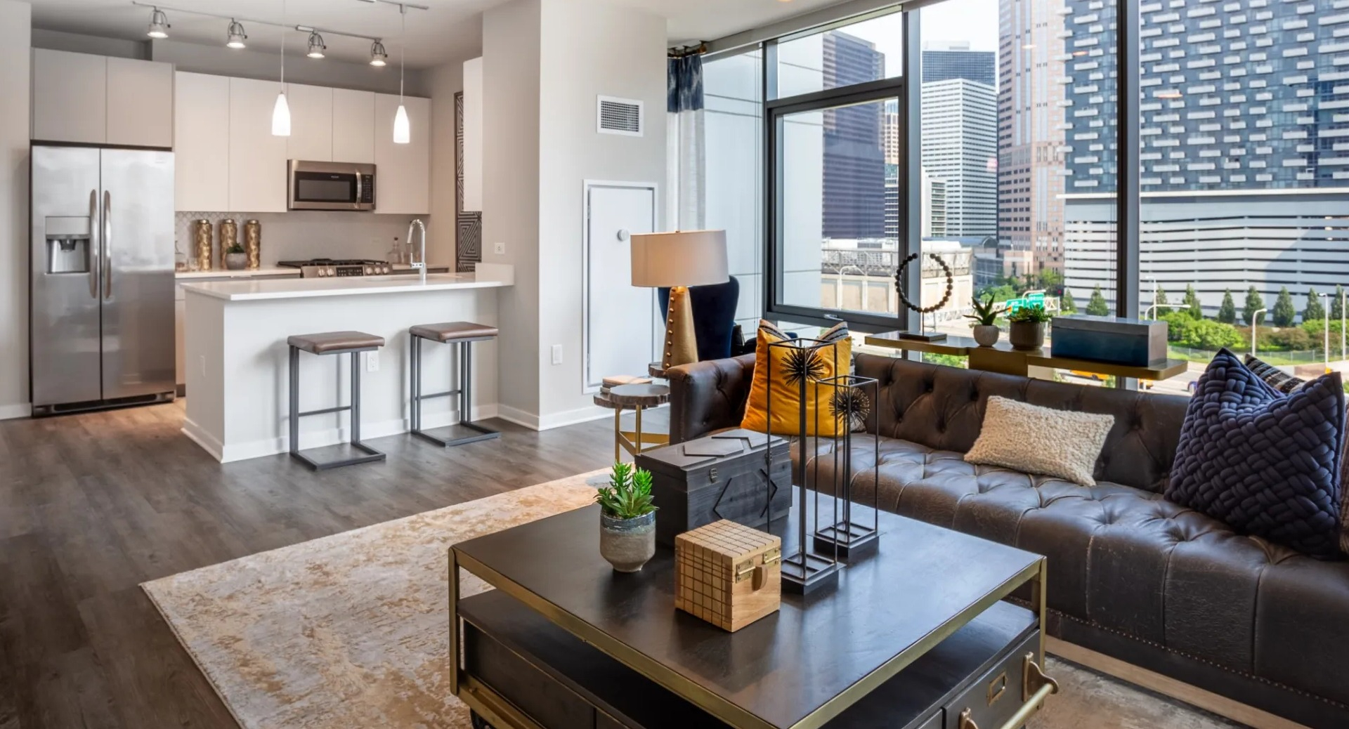 Modern open-concept kitchen and living room at The Grand Central Apartments in Chicago, featuring stainless steel appliances and city views