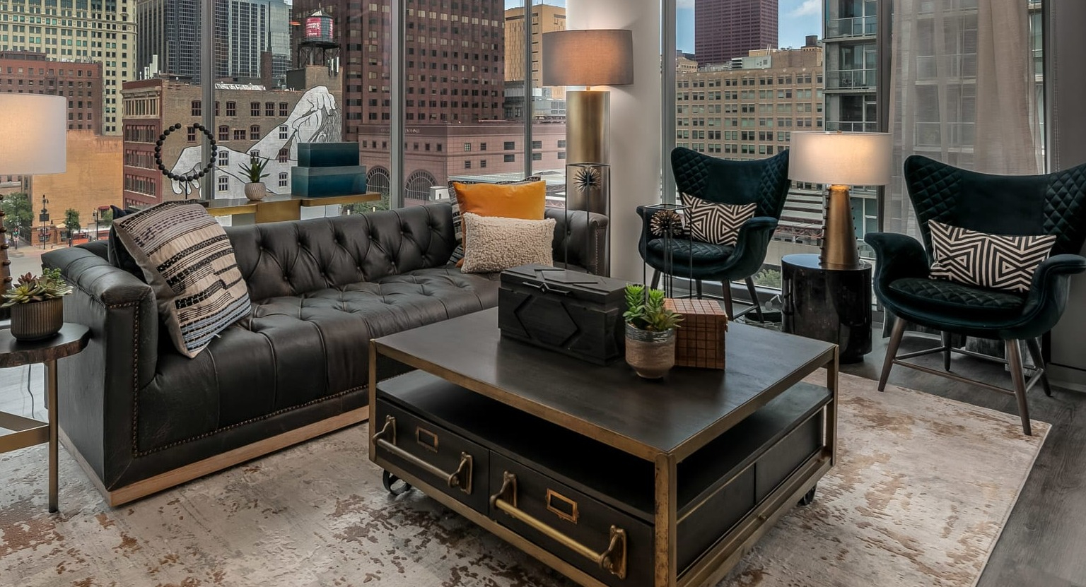 Luxurious apartment living room at The Grand Central Apartments in Chicago, featuring a black leather sofa and expansive city views