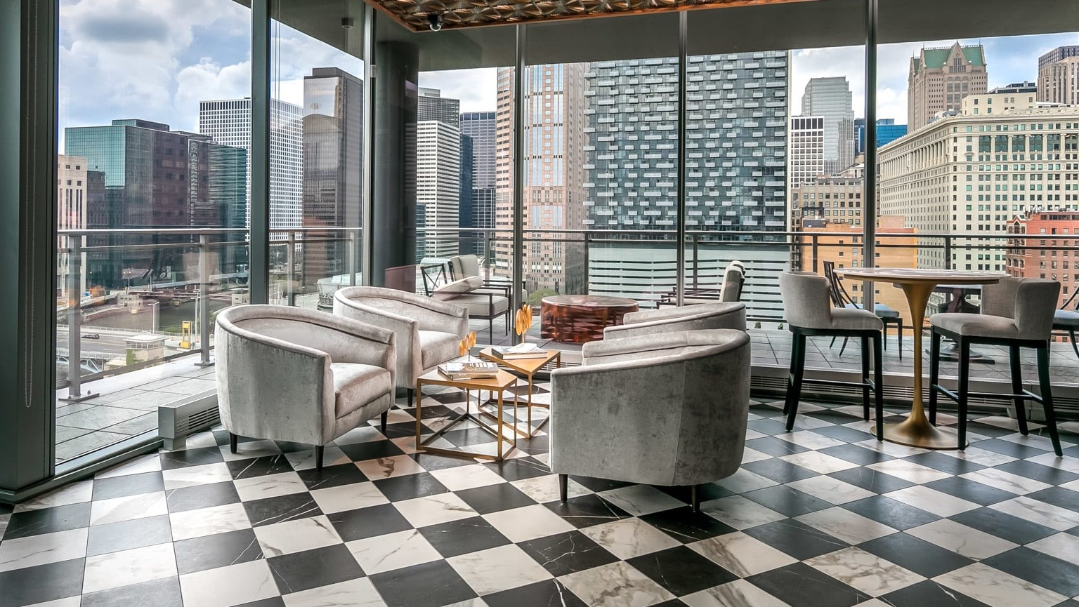 Stylish bar and lounge area at The Grand Central Apartments in Chicago, featuring unique decor, checkerboard floor, and expansive city views