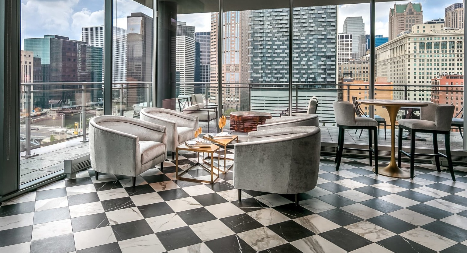 Stylish bar and lounge area at The Grand Central Apartments in Chicago, featuring unique decor, checkerboard floor, and expansive city views