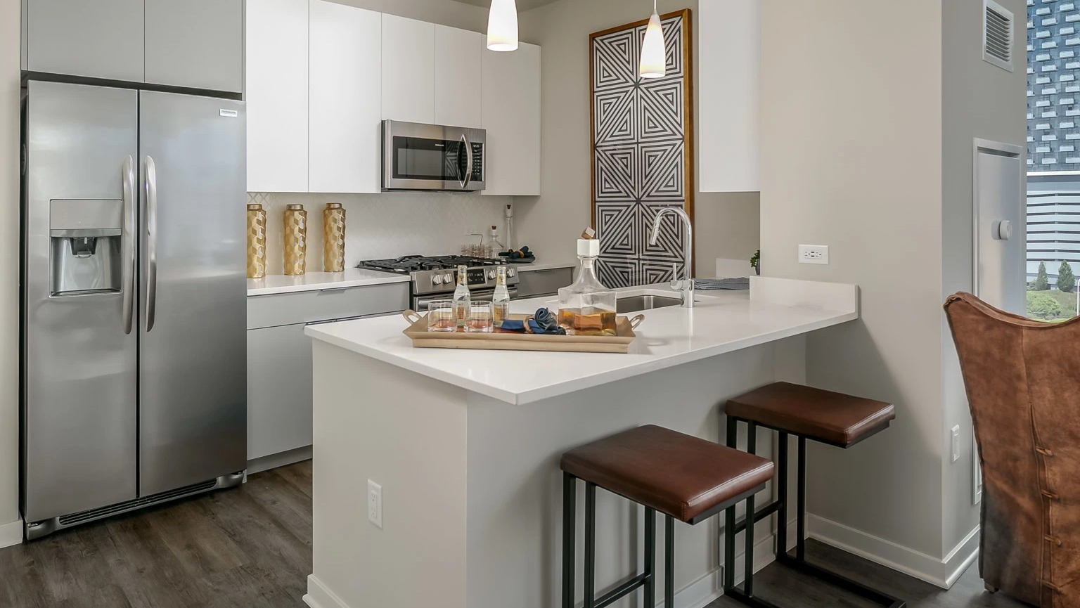 Modern apartment kitchen at The Grand Central Apartments in Chicago, featuring white cabinetry, stainless steel appliances, and a breakfast bar