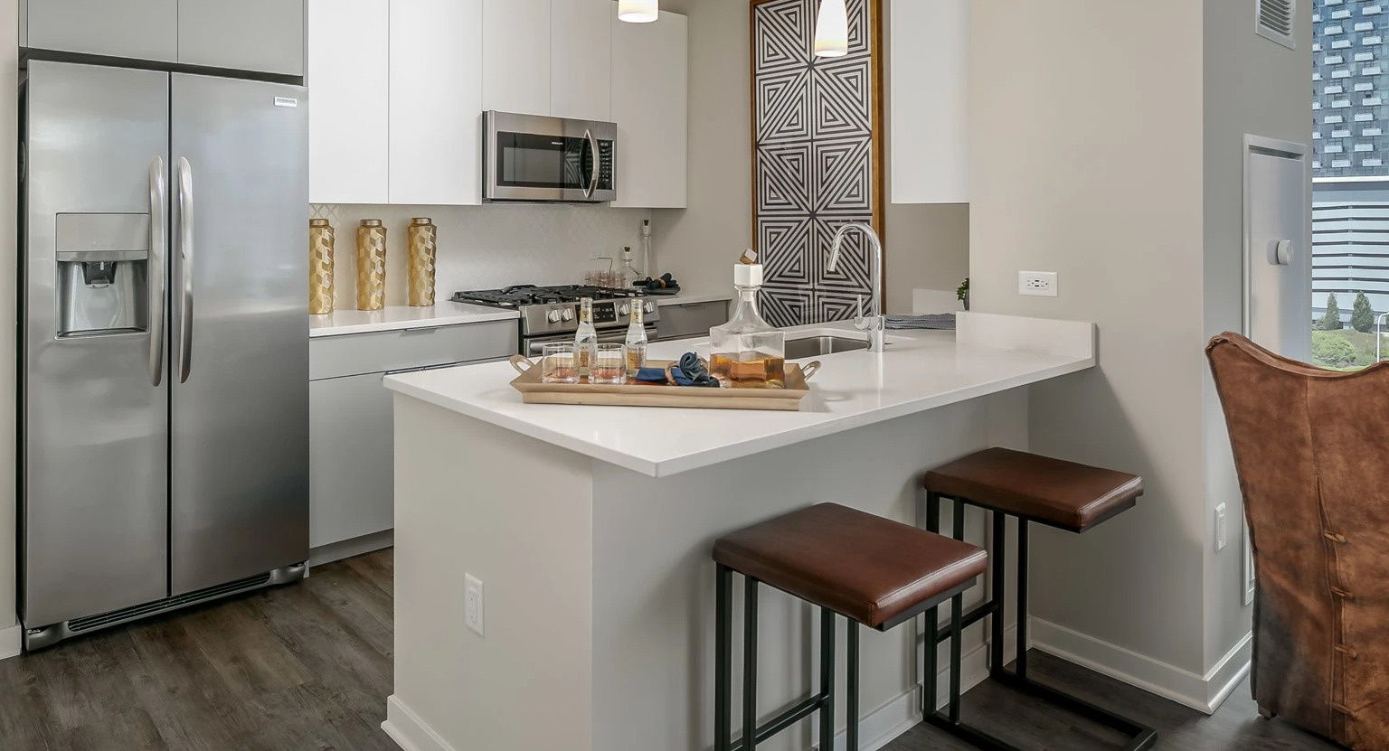 Modern apartment kitchen at The Grand Central Apartments in Chicago, featuring white cabinetry, stainless steel appliances, and a breakfast bar