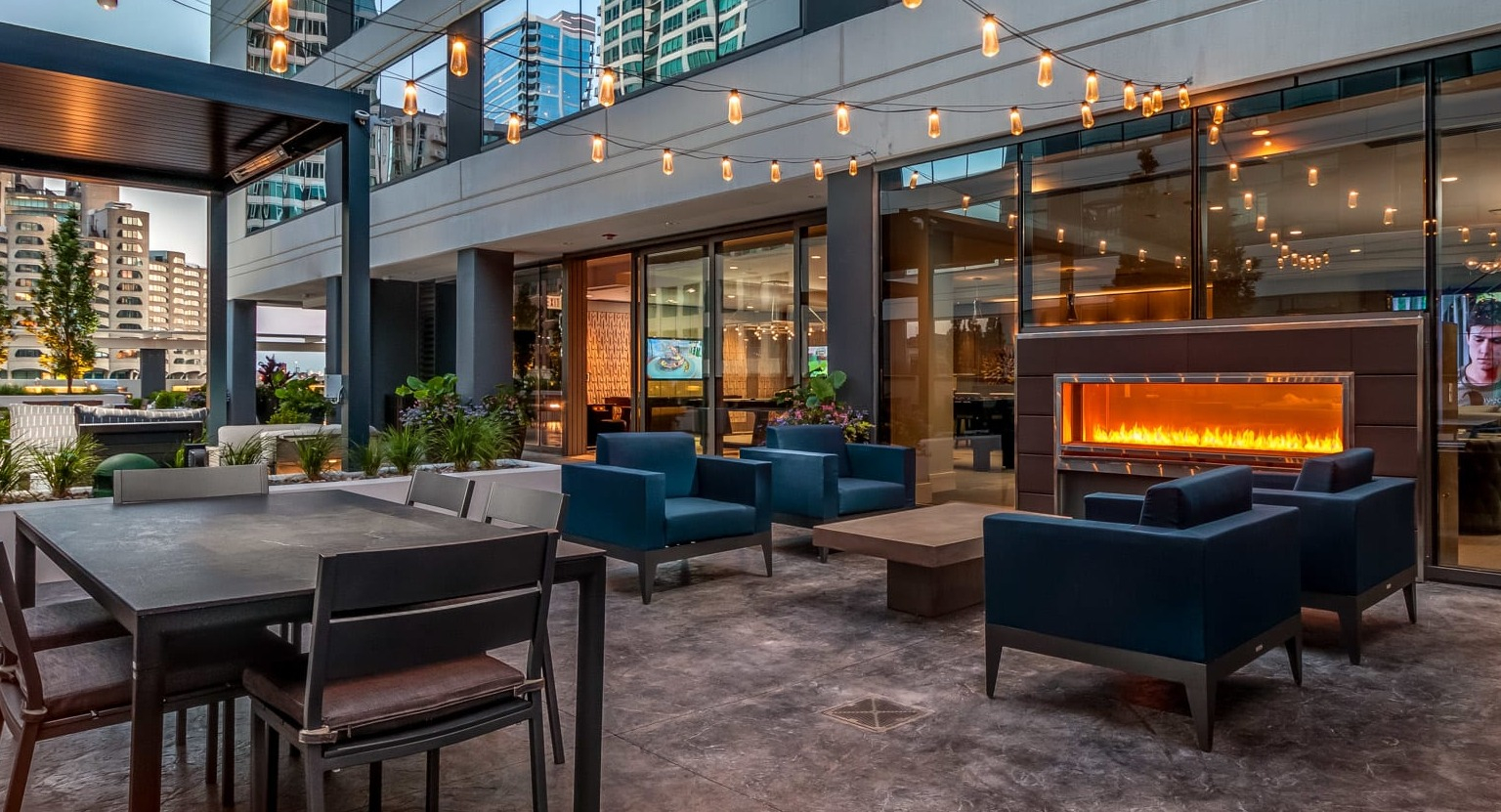 Inviting outdoor patio at The Grand Central Apartments in Chicago, featuring a cozy fireplace, string lights, and seating areas