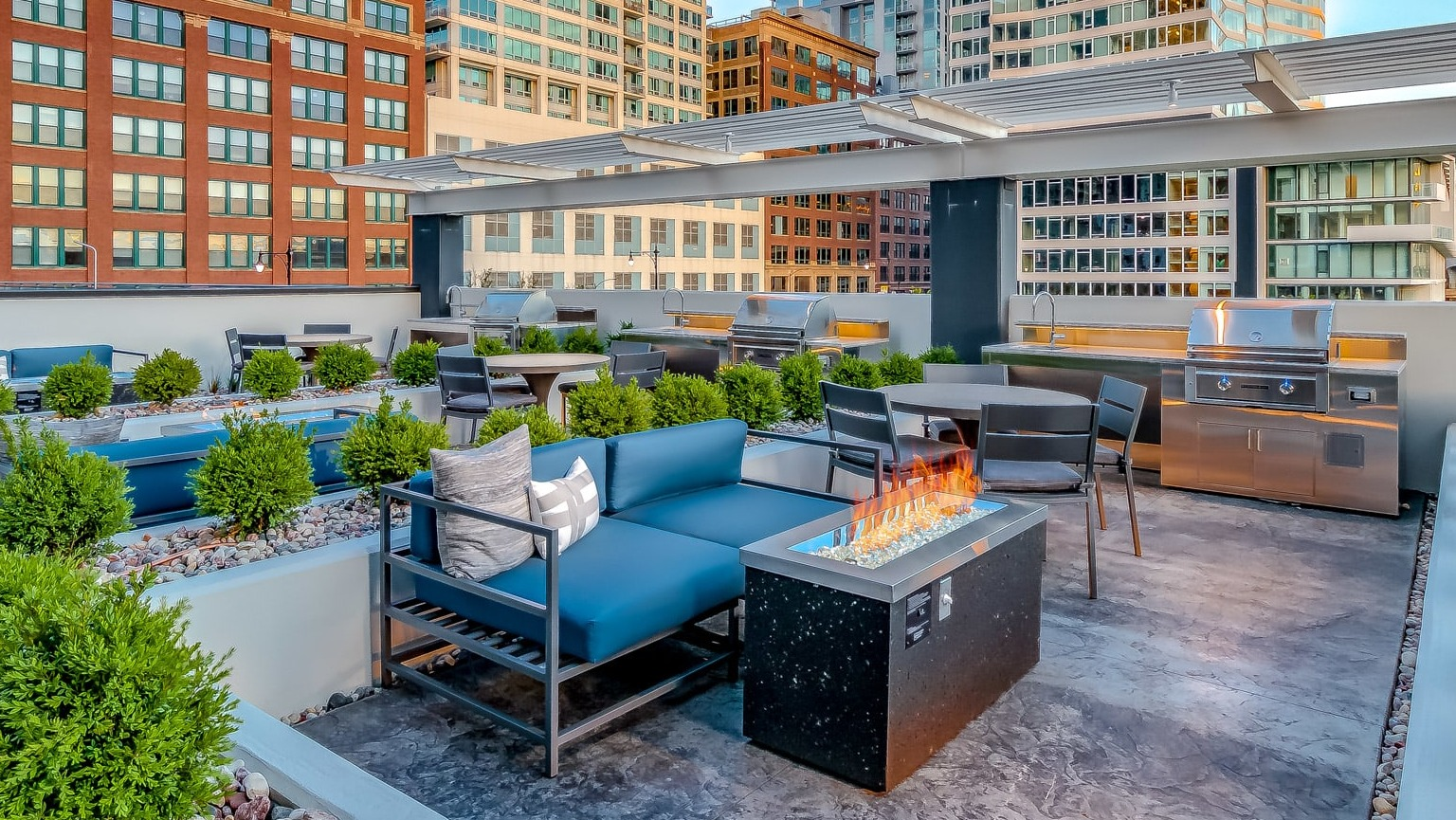 Expansive rooftop lounge at The Grand Central Apartments in Chicago, featuring comfortable sofas, a fire pit, and grilling stations