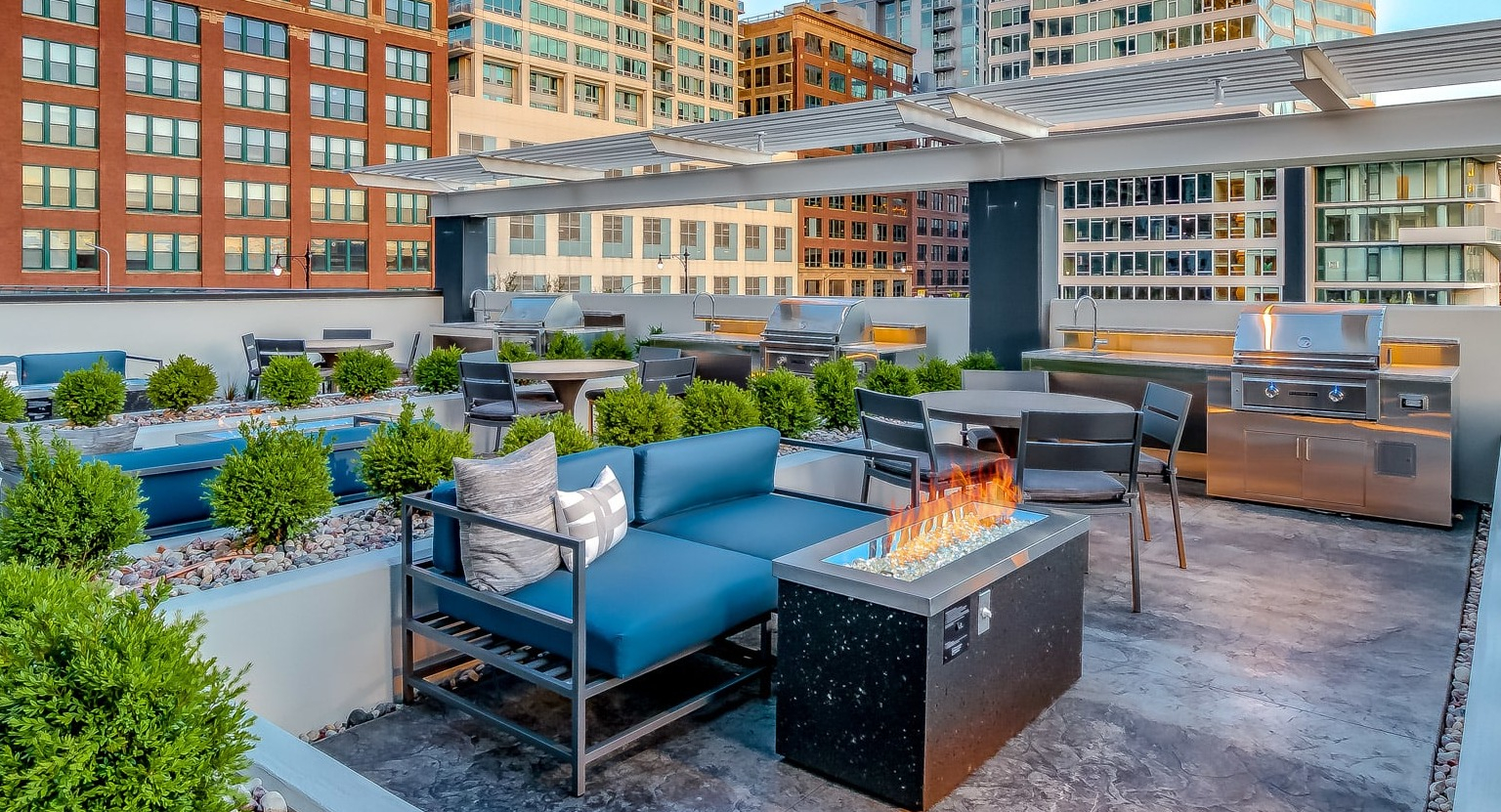 Expansive rooftop lounge at The Grand Central Apartments in Chicago, featuring comfortable sofas, a fire pit, and grilling stations