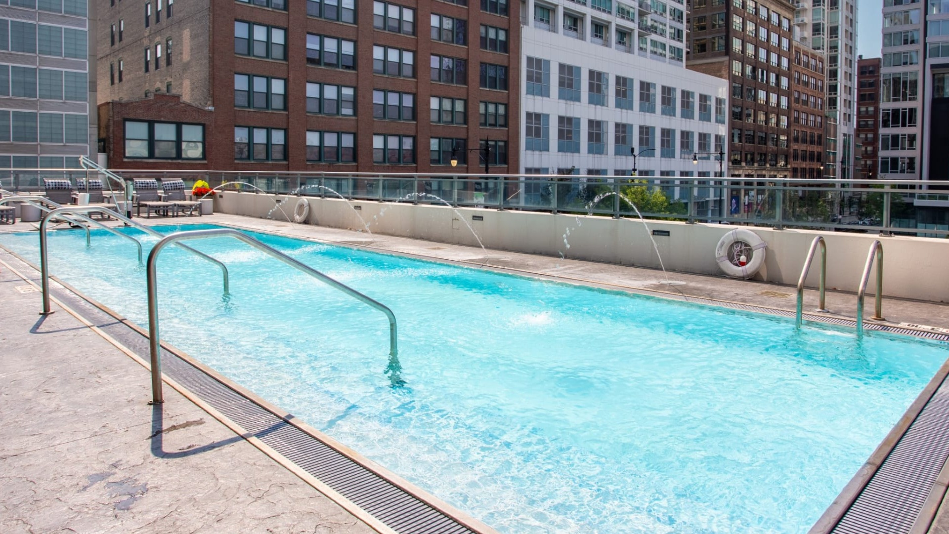 Inviting rooftop swimming pool at The Grand Central Apartments in Chicago, featuring water fountains and city buildings in the background