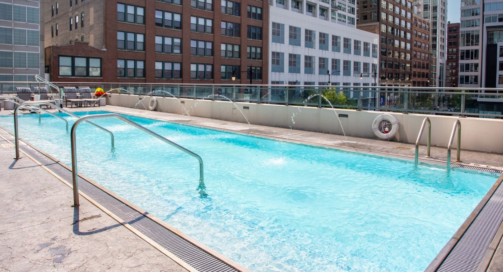Inviting rooftop swimming pool at The Grand Central Apartments in Chicago, featuring water fountains and city buildings in the background