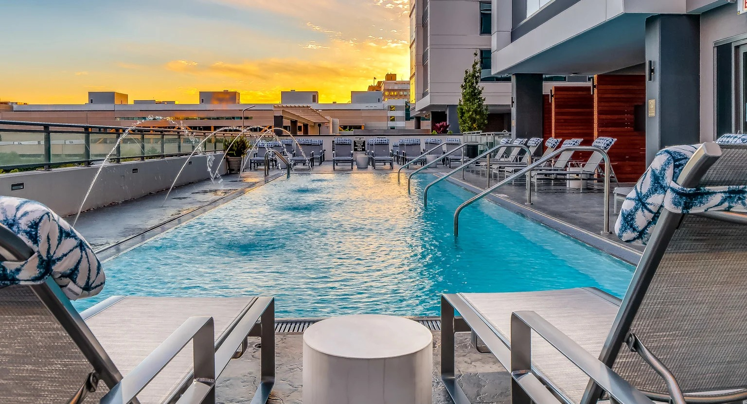 Stunning sunset view from the rooftop pool lounge at The Grand Central Apartments in Chicago, featuring lounge chairs and illuminated water
