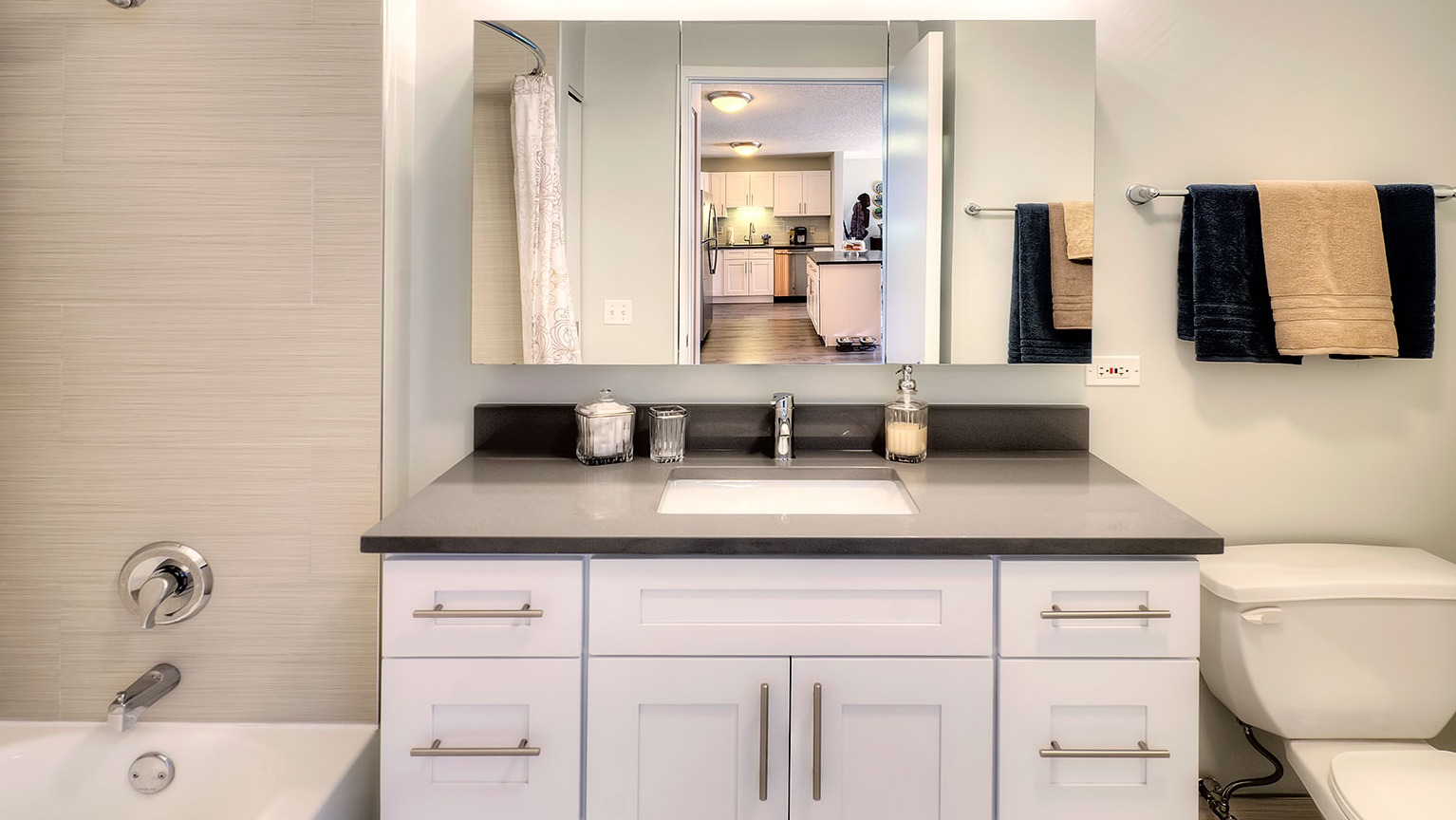 Modern bathroom featuring a spacious vanity, large mirror, and a combined tub and shower at Grand Plaza apartments in Chicago