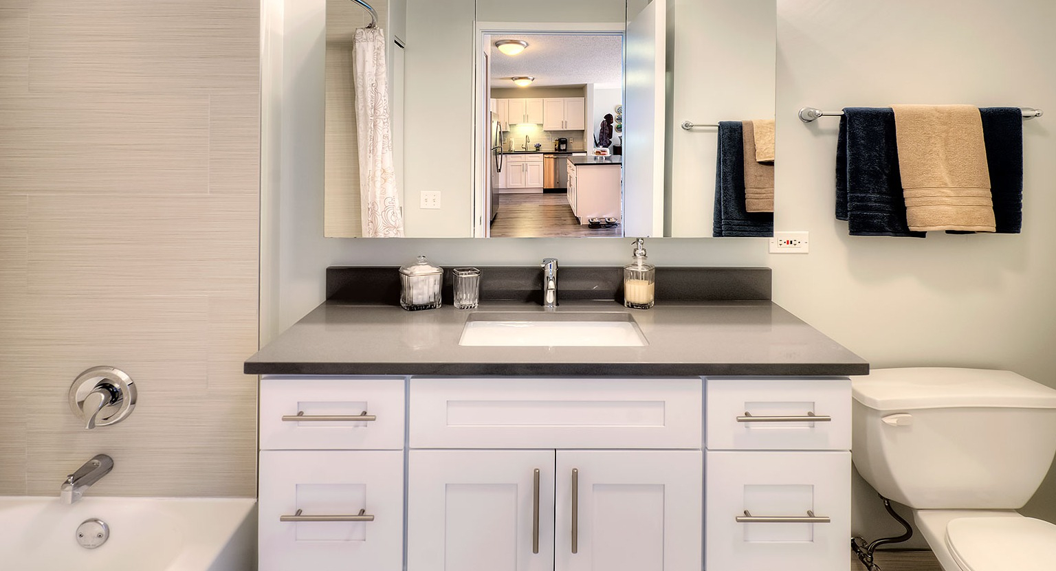 Modern bathroom featuring a spacious vanity, large mirror, and a combined tub and shower at Grand Plaza apartments in Chicago