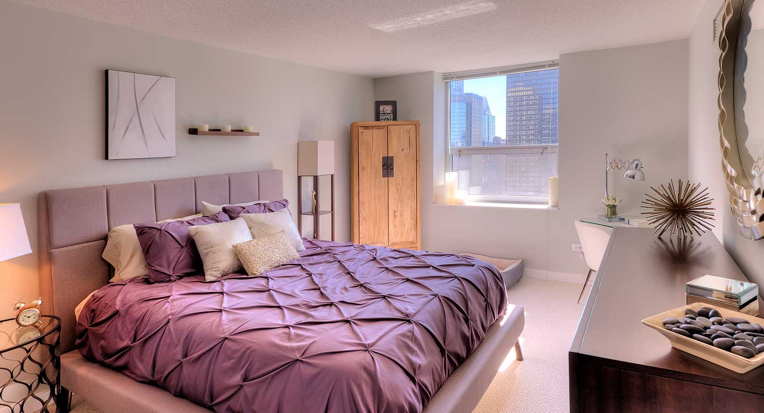 Spacious bedroom with a comfortable bed, stylish decor, and city views from the window at Grand Plaza apartments in Chicago