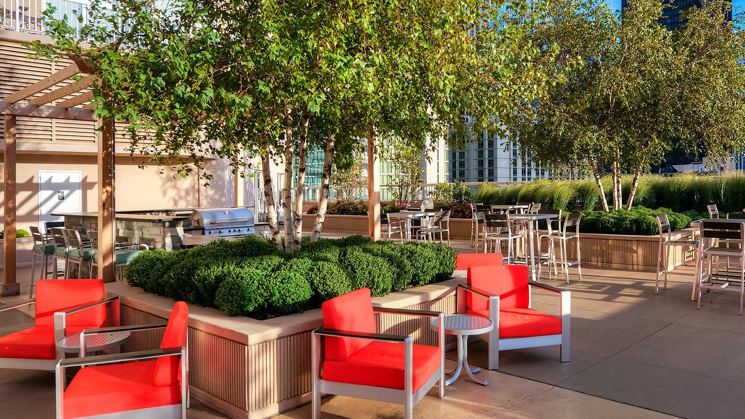 Green courtyard area with ample seating, trees, and outdoor grills, ideal for socializing at Grand Plaza apartments in Chicago
