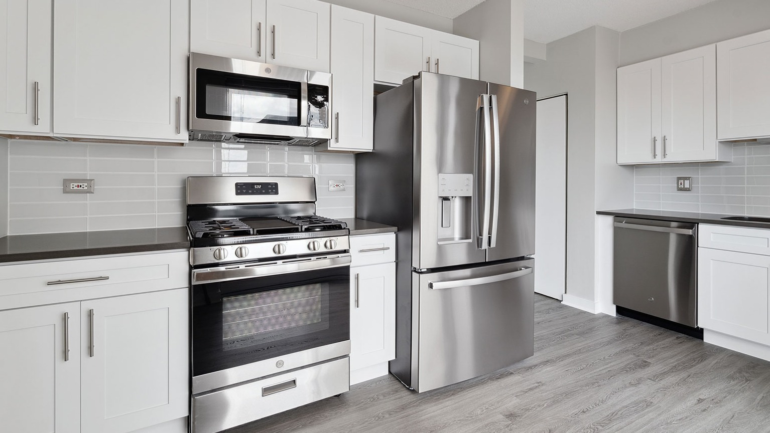 Contemporary kitchen equipped with modern stainless steel appliances and subway tile backsplash at Grand Plaza apartments in Chicago