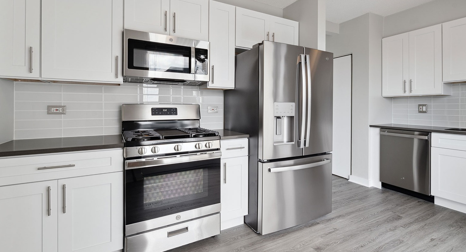 Contemporary kitchen equipped with modern stainless steel appliances and subway tile backsplash at Grand Plaza apartments in Chicago