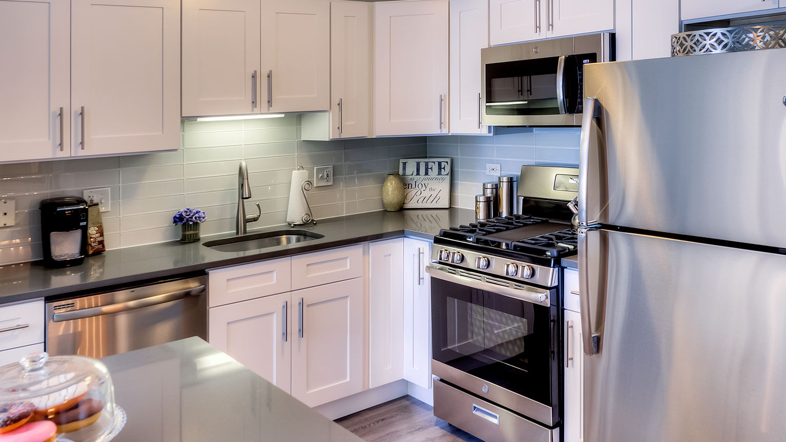 Modern kitchen with white cabinetry, stainless steel appliances, and ample counter space at Grand Plaza apartments in Chicago