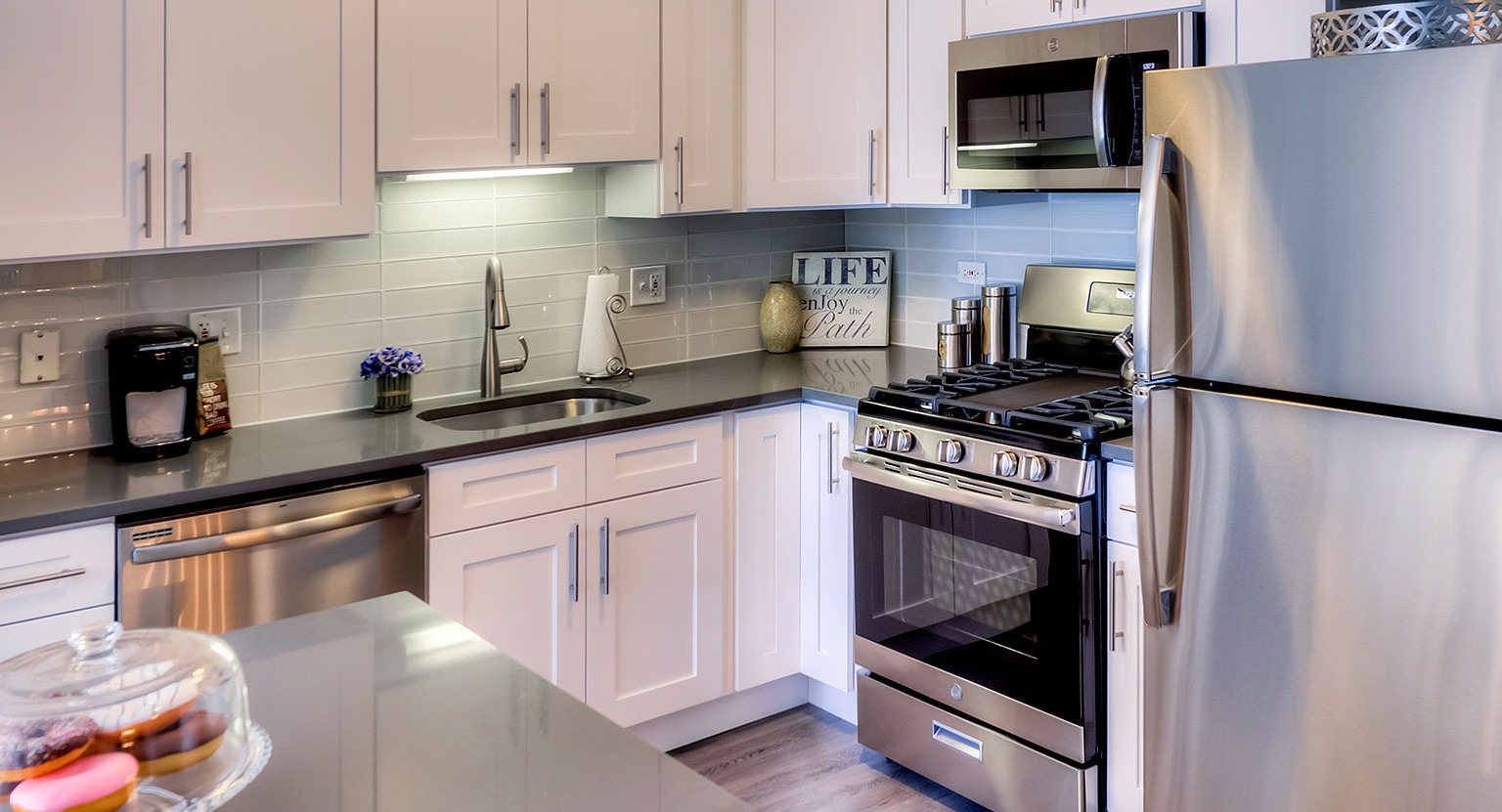 Modern kitchen with white cabinetry, stainless steel appliances, and ample counter space at Grand Plaza apartments in Chicago