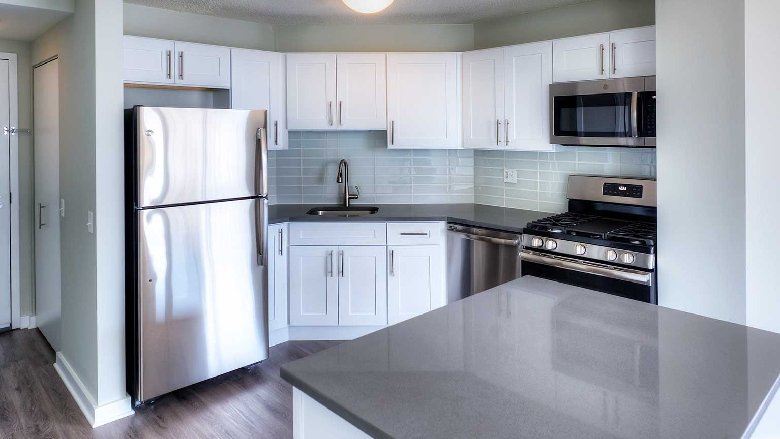 Bright kitchen with white cabinets, dark countertops, and stainless steel appliances at Grand Plaza apartments in Chicago