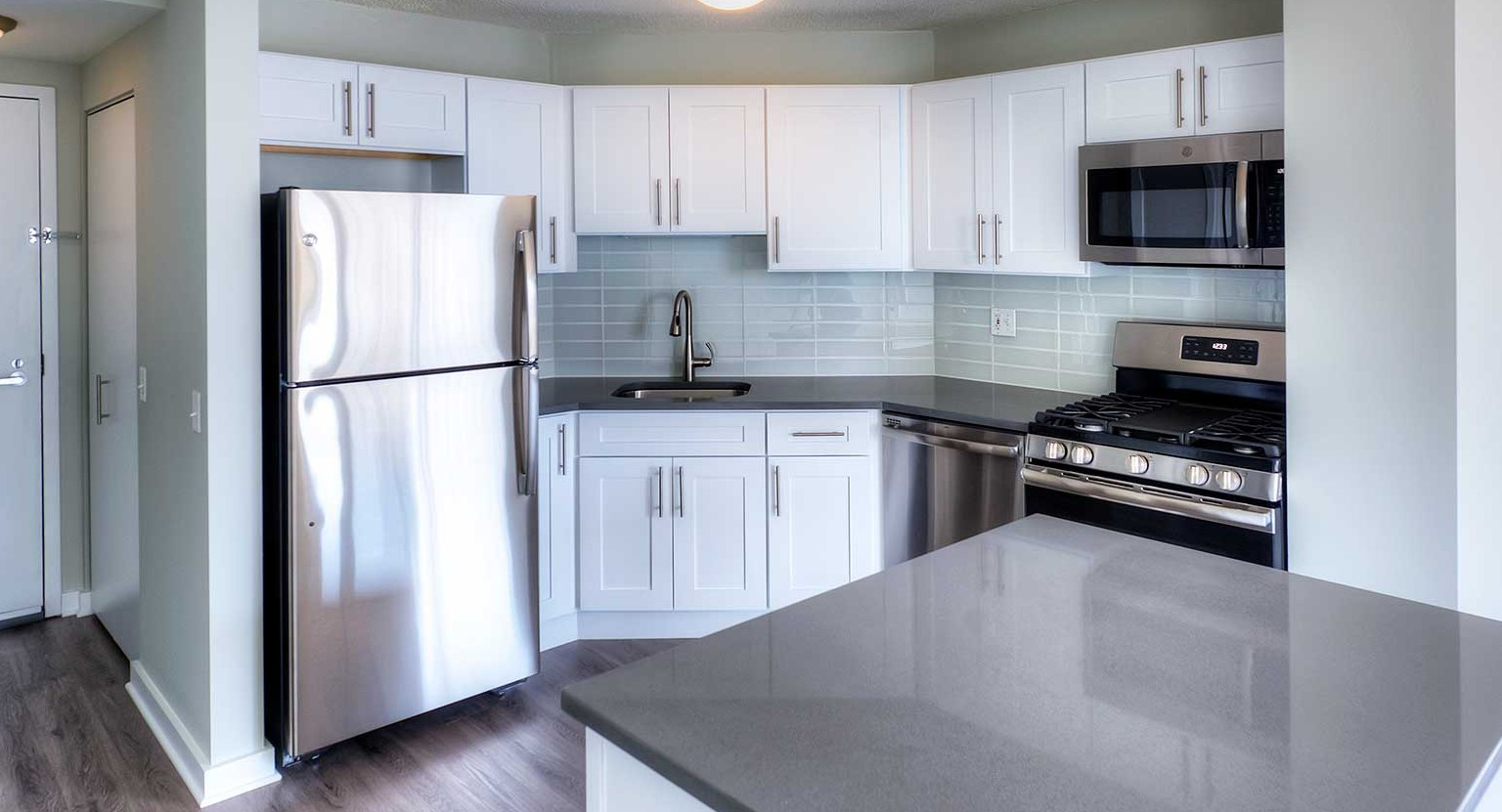 Bright kitchen with white cabinets, dark countertops, and stainless steel appliances at Grand Plaza apartments in Chicago