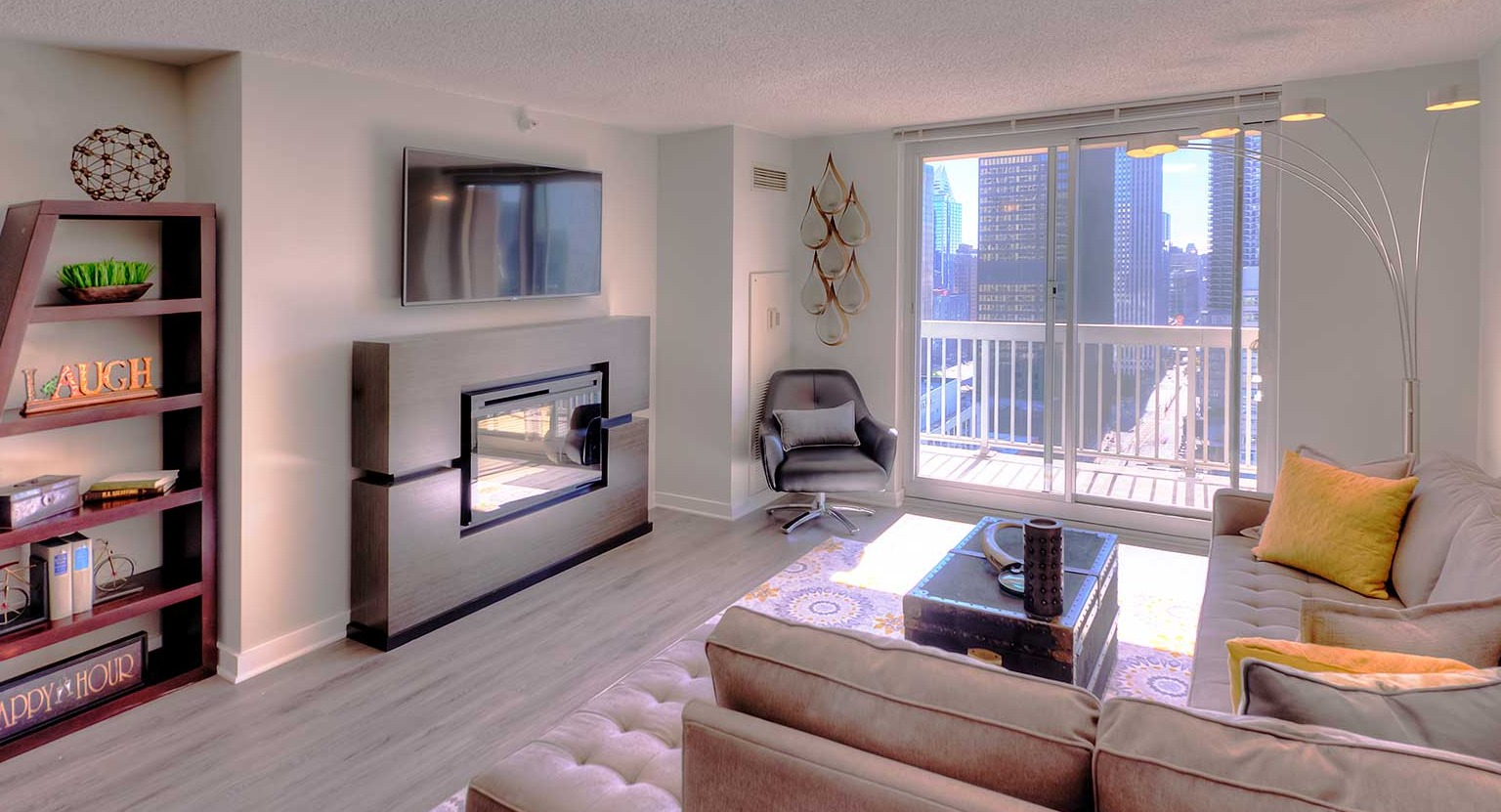 Stylish living room with a cozy fireplace, TV, and large windows offering city views at Grand Plaza apartments in Chicago
