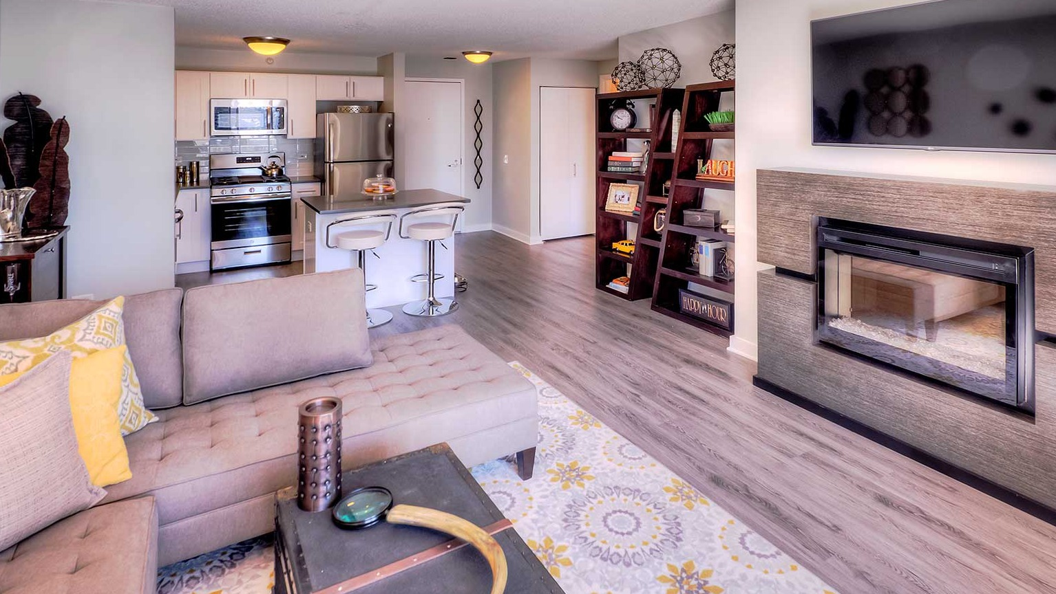 Open-concept living room and kitchen area featuring a modern fireplace and chic decor at Grand Plaza apartments in Chicago