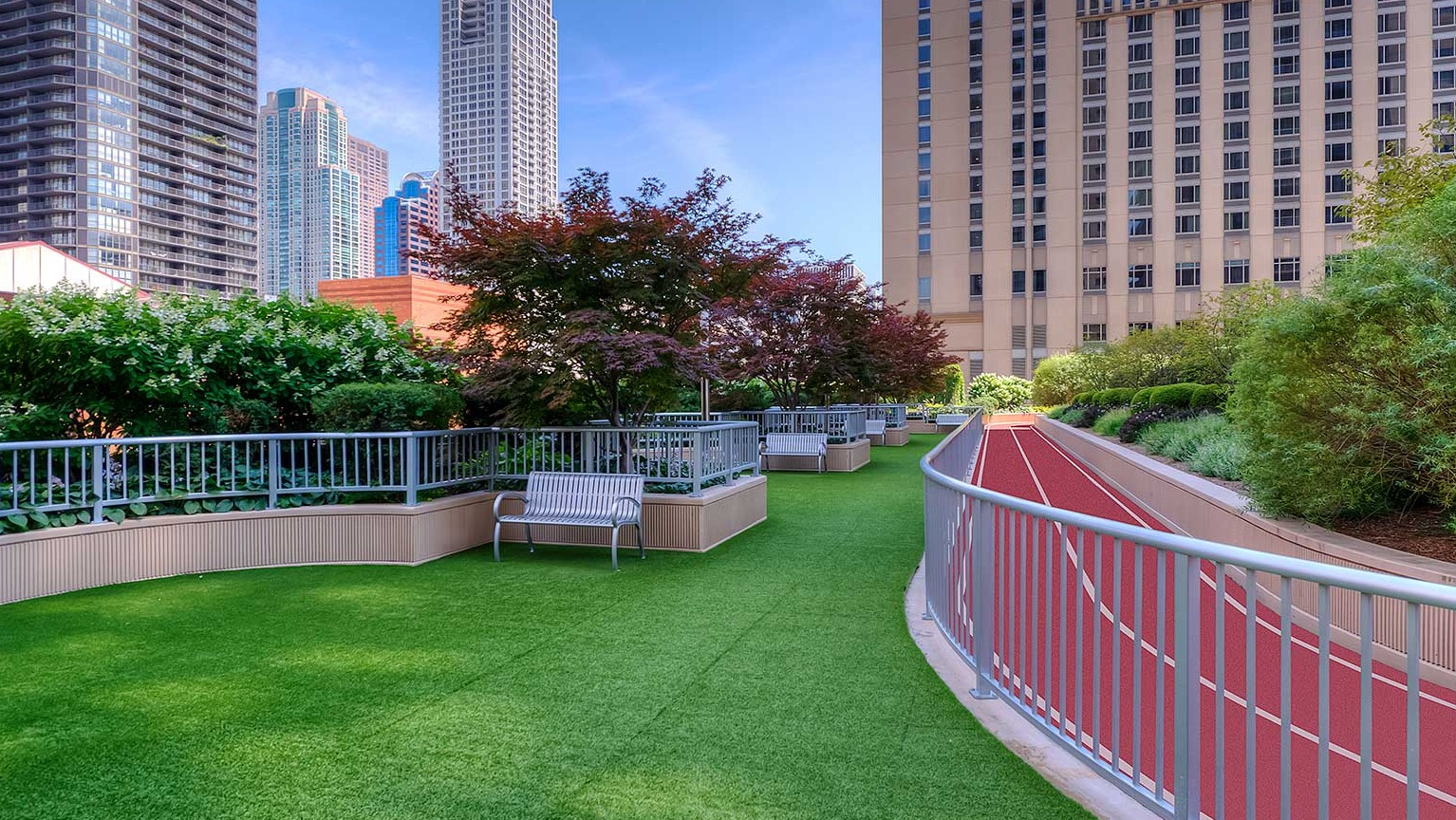 Outdoor running track alongside a green turf area, surrounded by lush landscaping and city views at Grand Plaza in Chicago