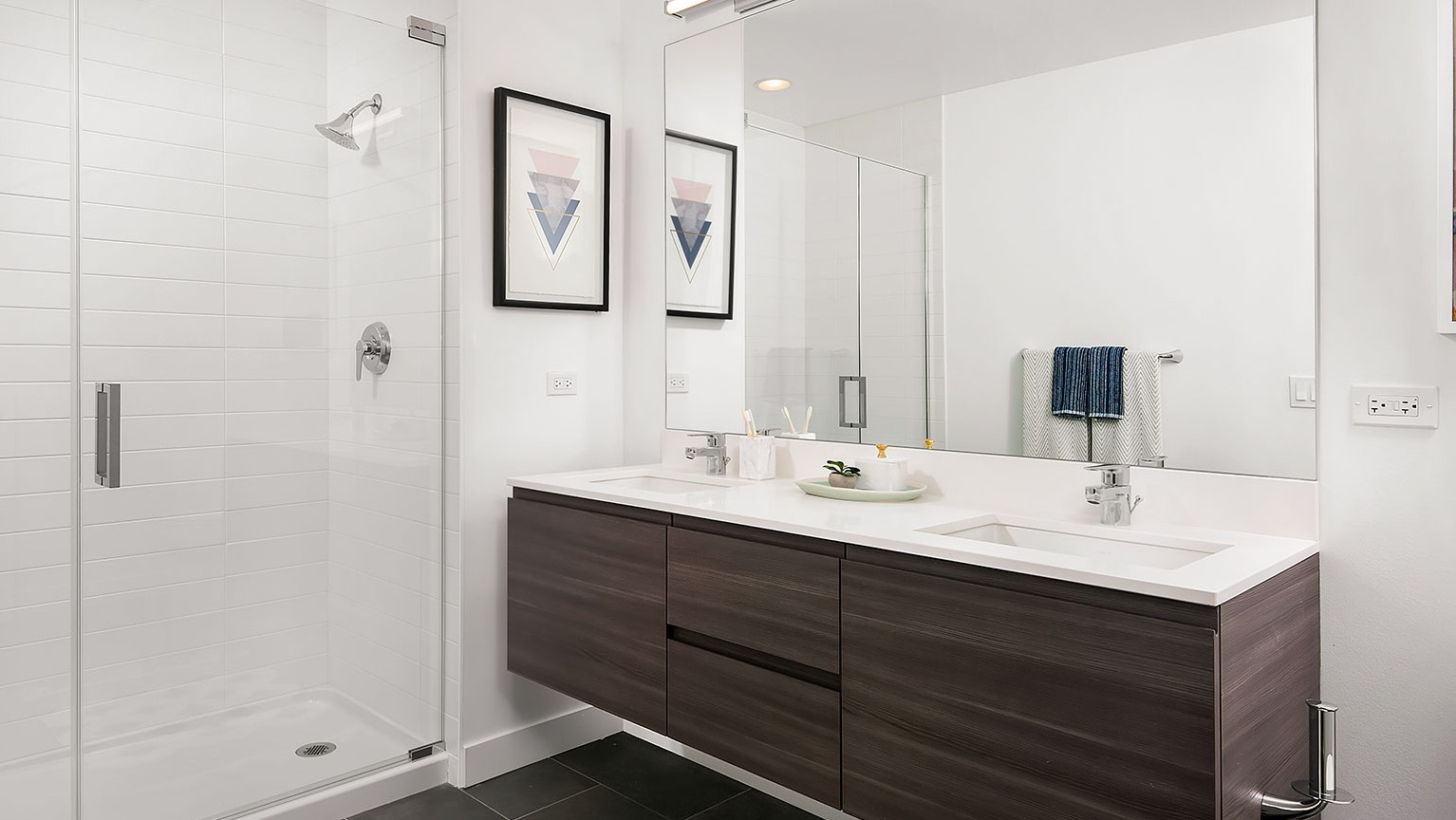 A sleek bathroom at Hubbard 221 with a double vanity, dark cabinetry, and a spacious walk-in shower