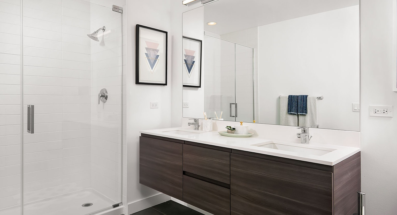 A sleek bathroom at Hubbard 221 with a double vanity, dark cabinetry, and a spacious walk-in shower