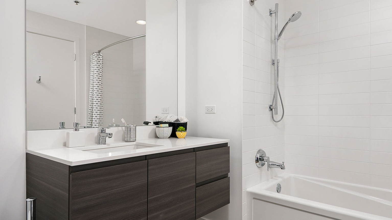 A clean and modern bathroom at Hubbard 221 featuring a dark wood vanity, white subway tile, and a spacious bathtub