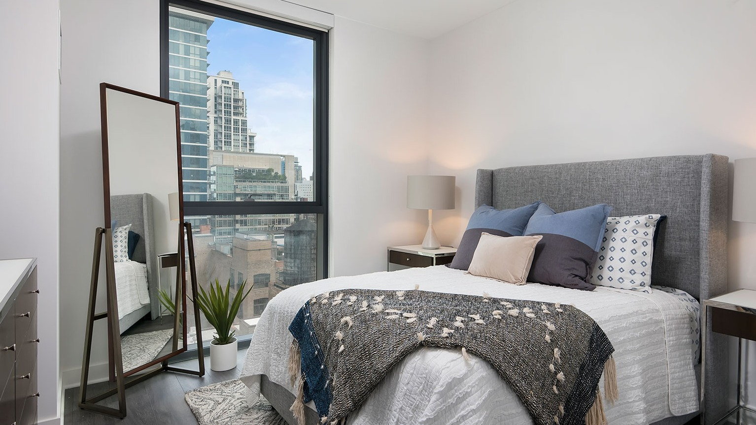 A cozy and modern bedroom at Hubbard 221 with a large window offering impressive city views and stylish decor