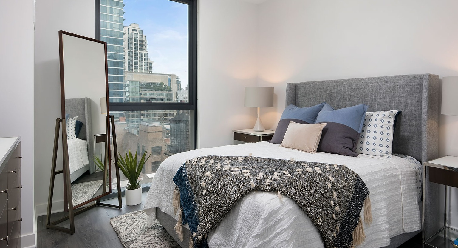 A cozy and modern bedroom at Hubbard 221 with a large window offering impressive city views and stylish decor