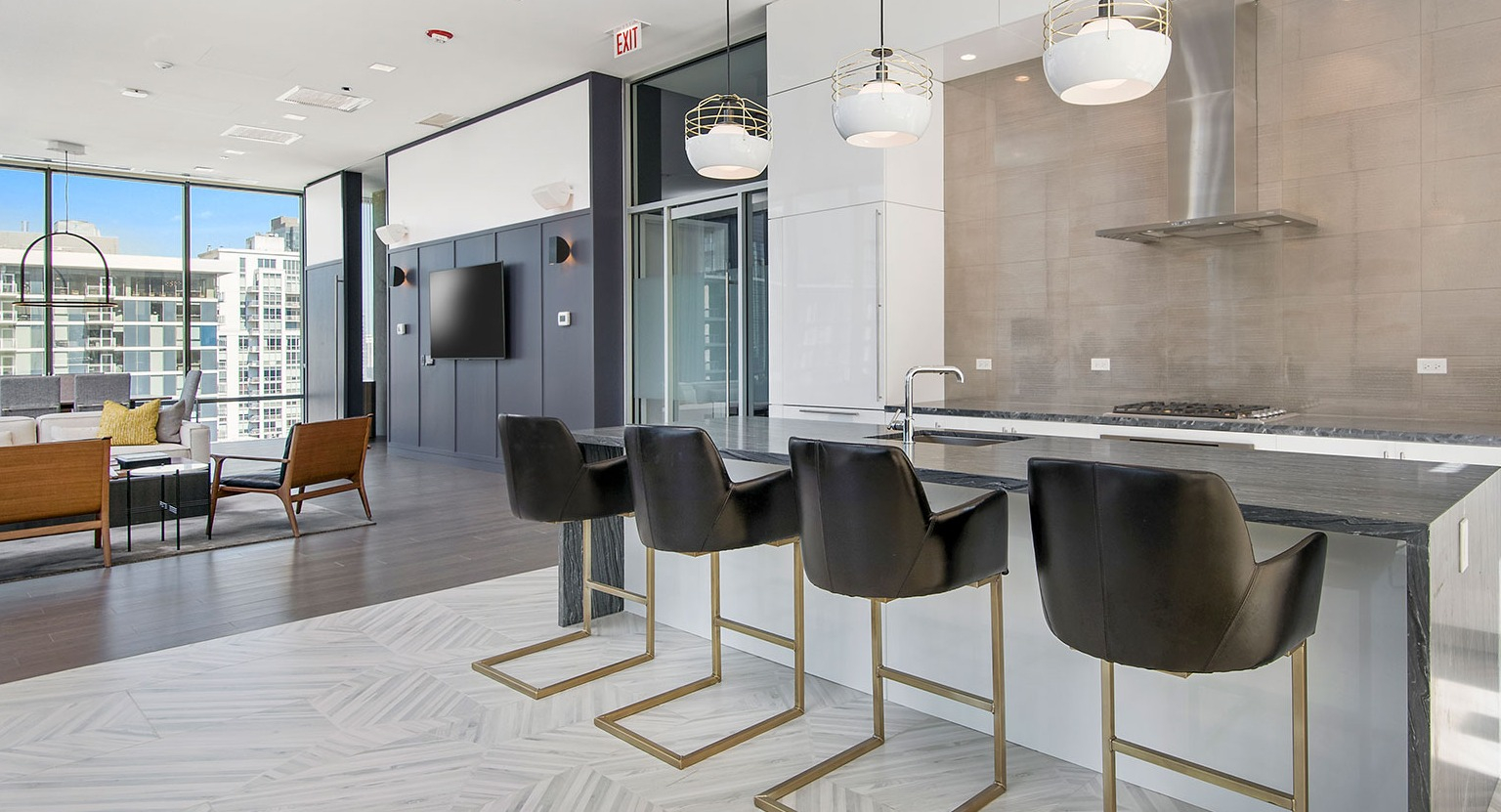 A stylish community kitchen and lounge area at Hubbard 221, featuring a large island, bar seating, and modern design