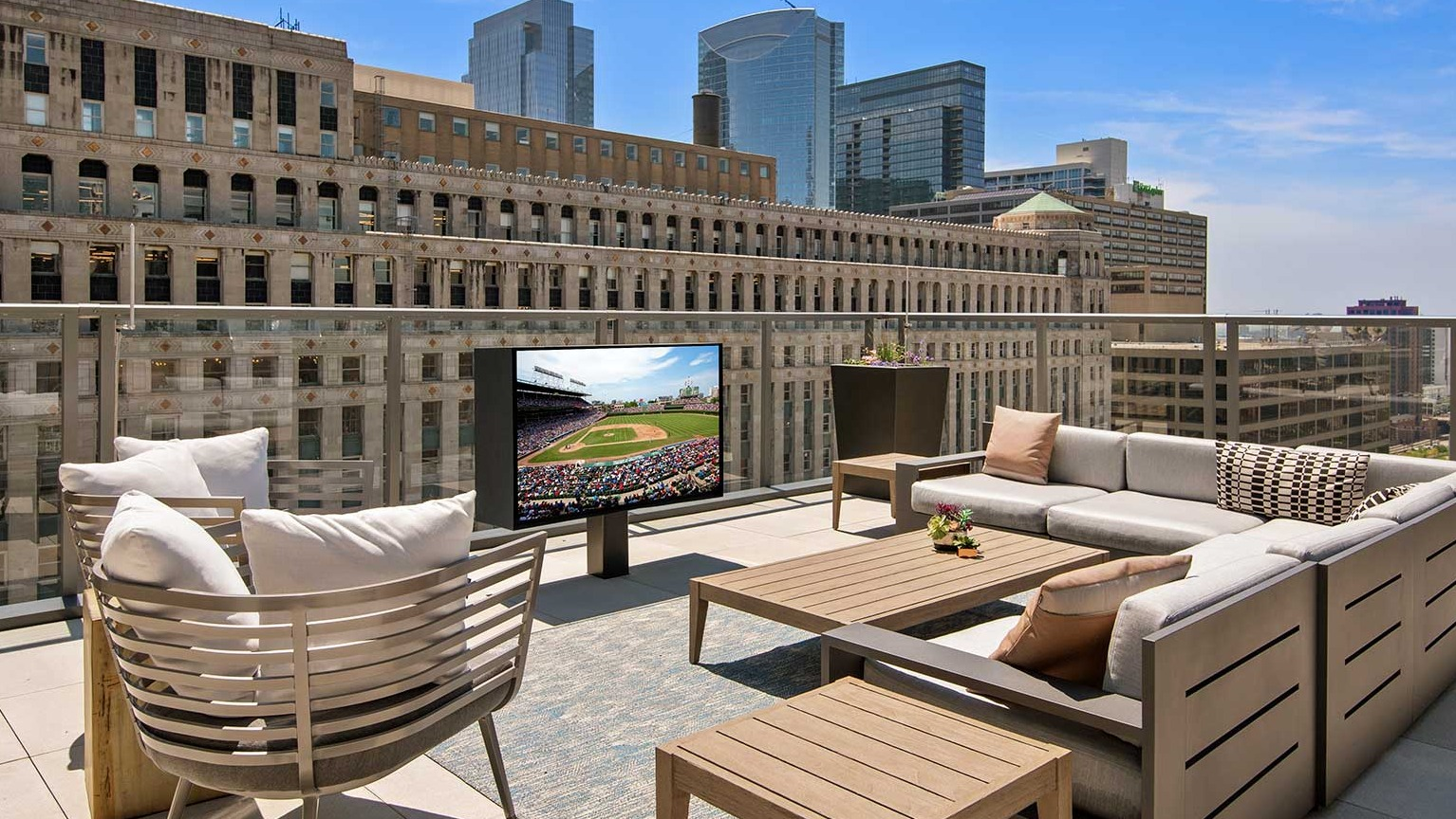 A spacious rooftop deck at Hubbard 221 featuring comfortable seating, an outdoor TV, and expansive city views