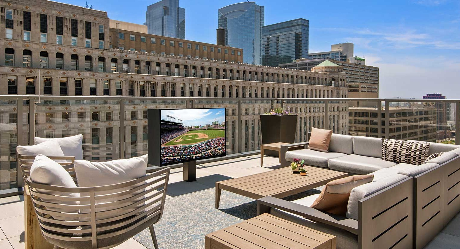 A spacious rooftop deck at Hubbard 221 featuring comfortable seating, an outdoor TV, and expansive city views