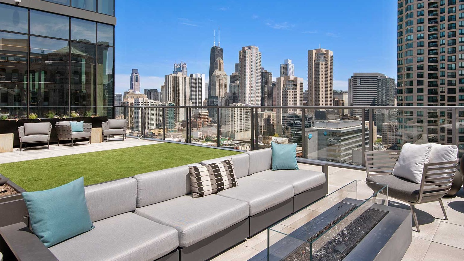 A chic rooftop lounge at Hubbard 221 with a fire pit, comfortable sofas, and panoramic views of the Chicago skyline