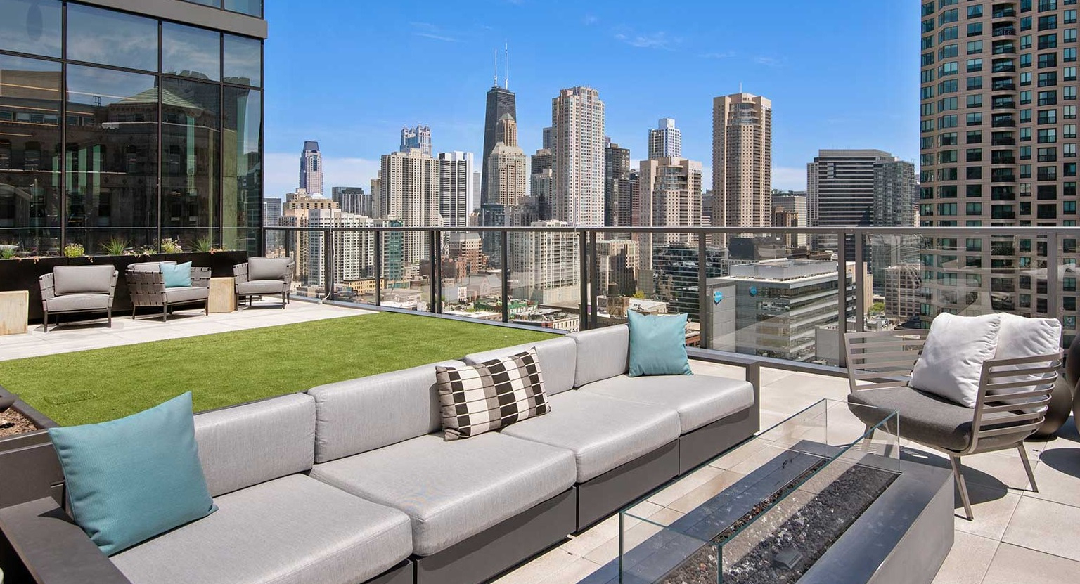 A chic rooftop lounge at Hubbard 221 with a fire pit, comfortable sofas, and panoramic views of the Chicago skyline