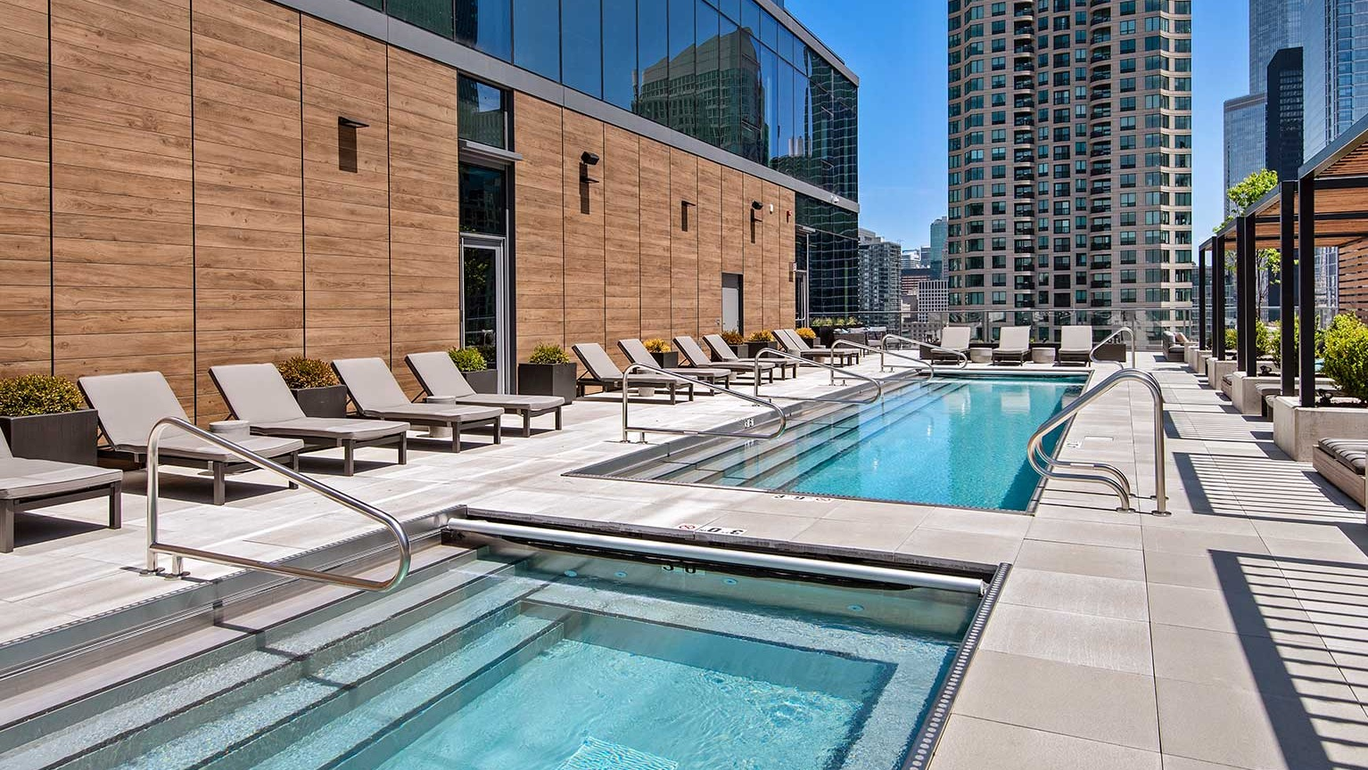 A luxurious rooftop pool and spa area at Hubbard 221 with lounge chairs and stunning city architecture in Chicago