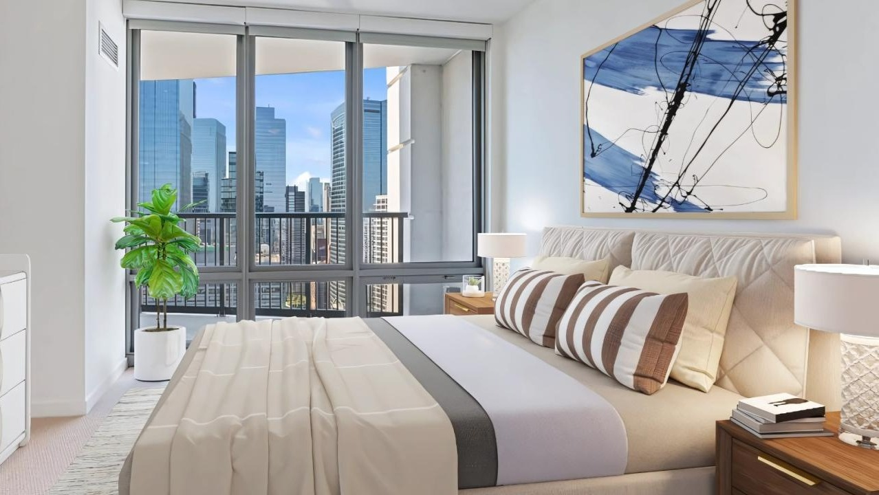 A cozy bedroom with stylish bedding, modern decor, and large windows offering cityscape views at Hubbard Place in Chicago
