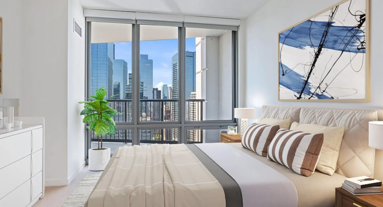 A cozy bedroom with stylish bedding, modern decor, and large windows offering cityscape views at Hubbard Place in Chicago