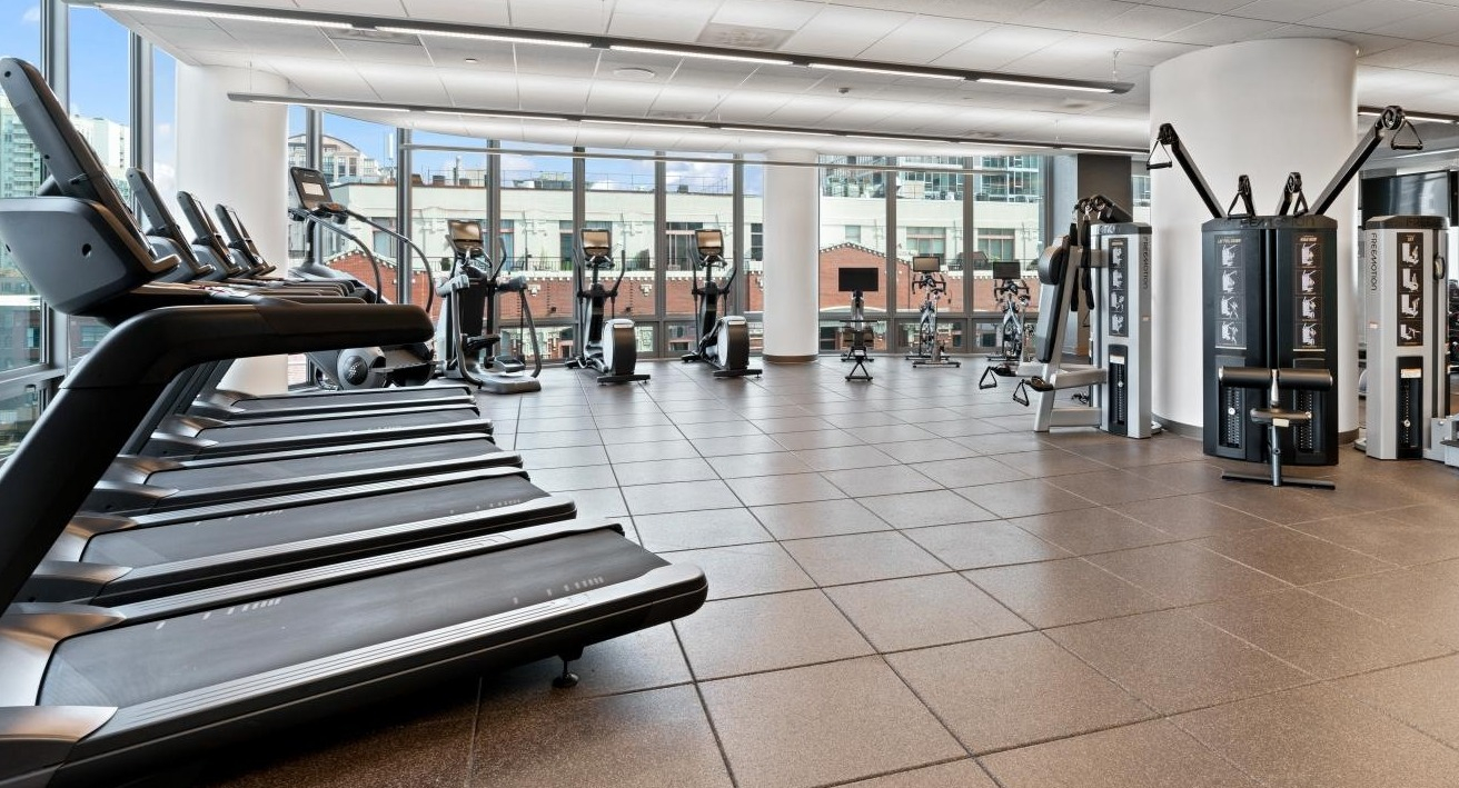 Spacious fitness center with a wide range of treadmills, weight machines, and free weights at Hubbard Place in Chicago