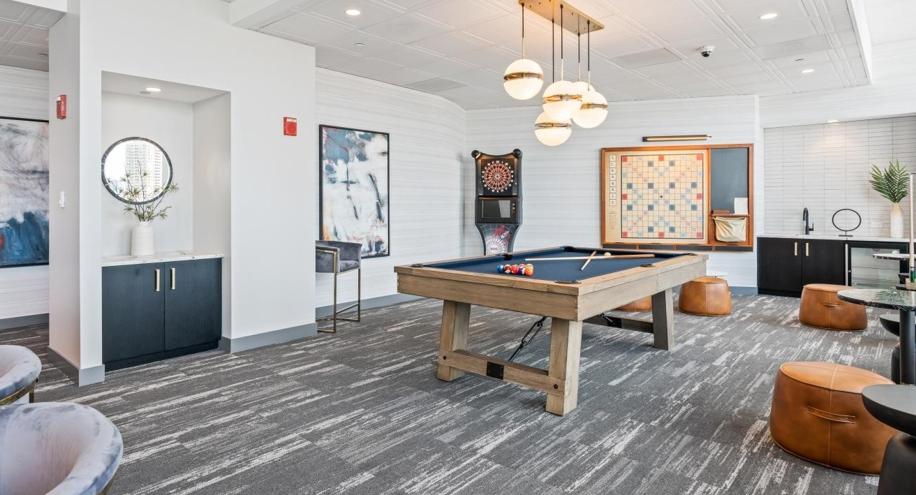 Stylish game room featuring a billiards table, comfortable seating, and various board games at Hubbard Place in Chicago