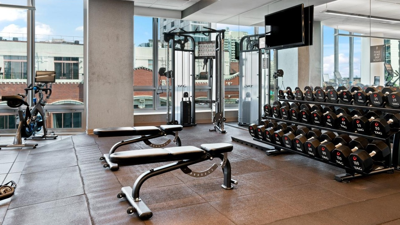 Well-equipped gym with free weights, weight benches, and various fitness machines at Hubbard Place in Chicago