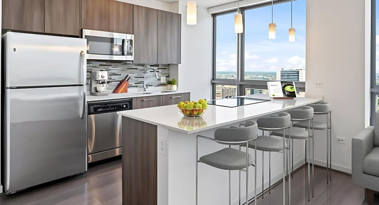 Modern kitchen with a large island, breakfast bar, stainless steel appliances, and impressive city views at Hubbard Place in Chicago