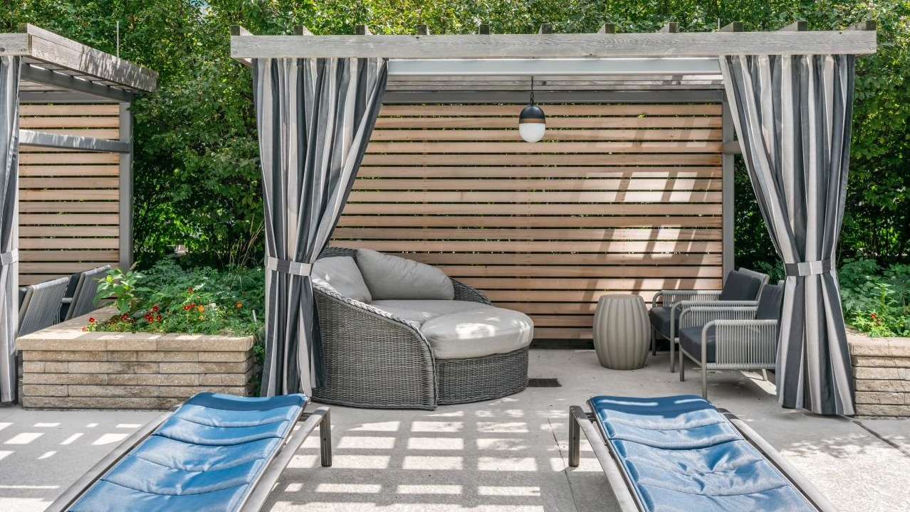 Outdoor lounge area with private cabanas and comfortable seating amidst lush greenery at Hubbard Place in Chicago