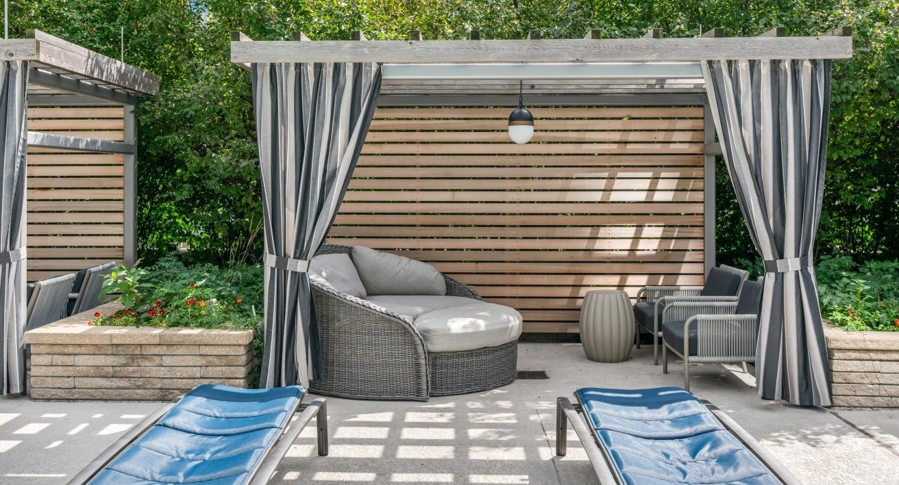Outdoor lounge area with private cabanas and comfortable seating amidst lush greenery at Hubbard Place in Chicago