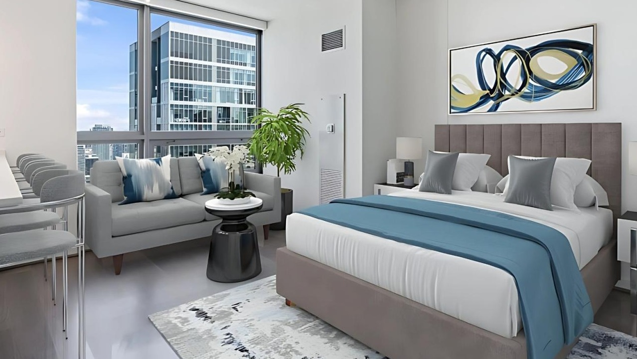 Contemporary studio apartment featuring a comfortable bed, a kitchenette with a breakfast bar, and city views at Hubbard Place in Chicago
