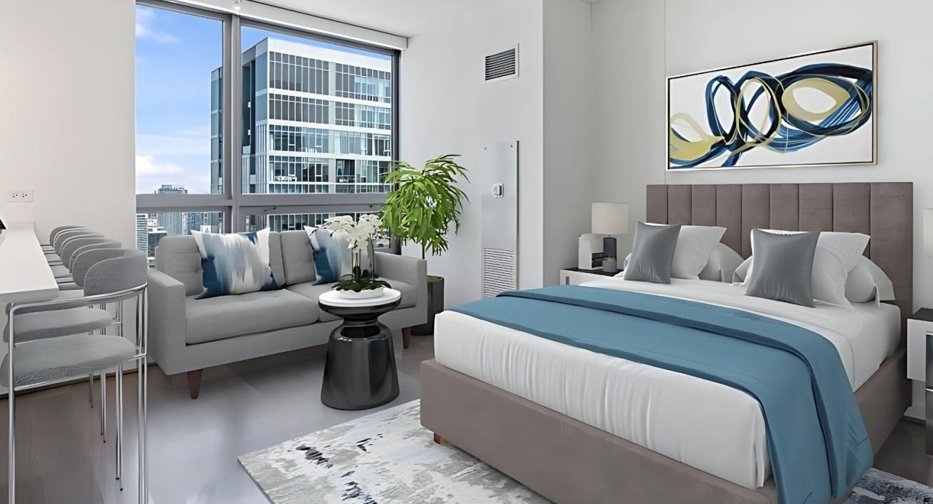 Contemporary studio apartment featuring a comfortable bed, a kitchenette with a breakfast bar, and city views at Hubbard Place in Chicago
