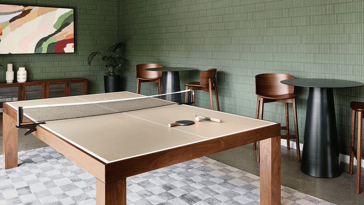 Vibrant game room featuring a ping-pong table and high-top seating, with modern green tiled walls at Hugo Apartments River North, Chicago
