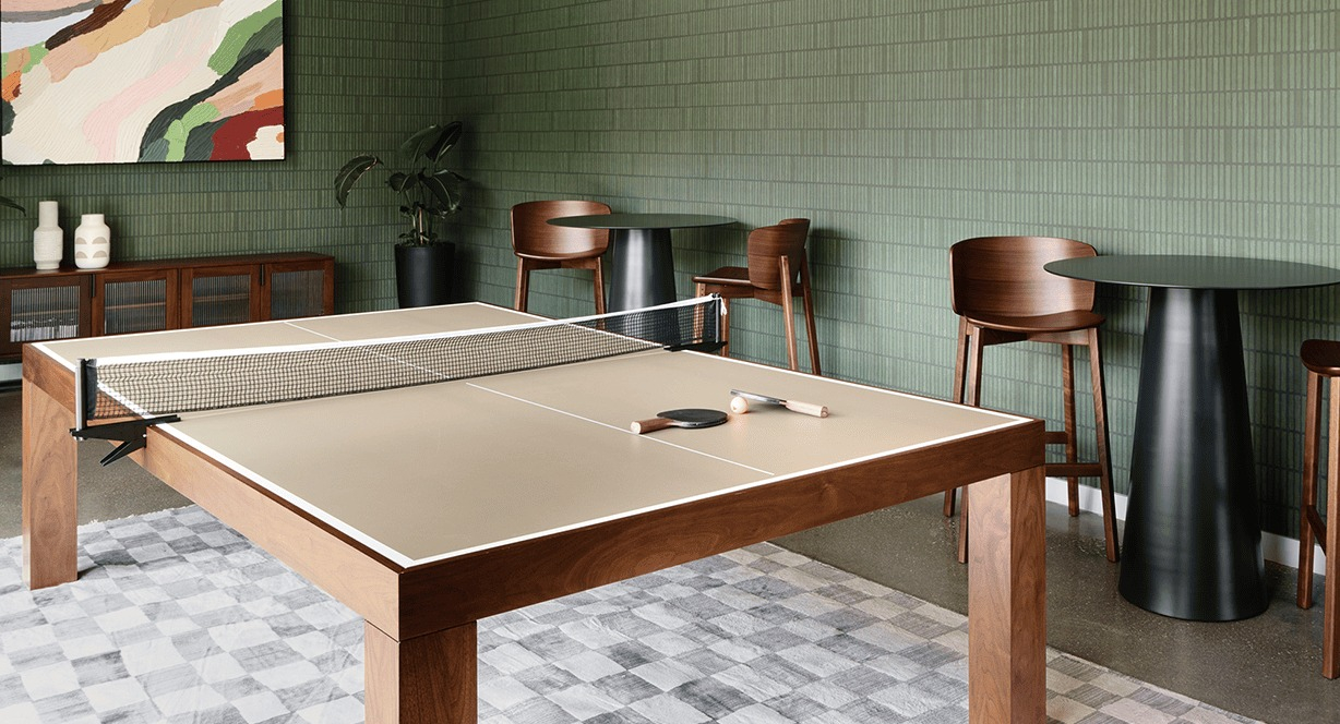Vibrant game room featuring a ping-pong table and high-top seating, with modern green tiled walls at Hugo Apartments River North, Chicago