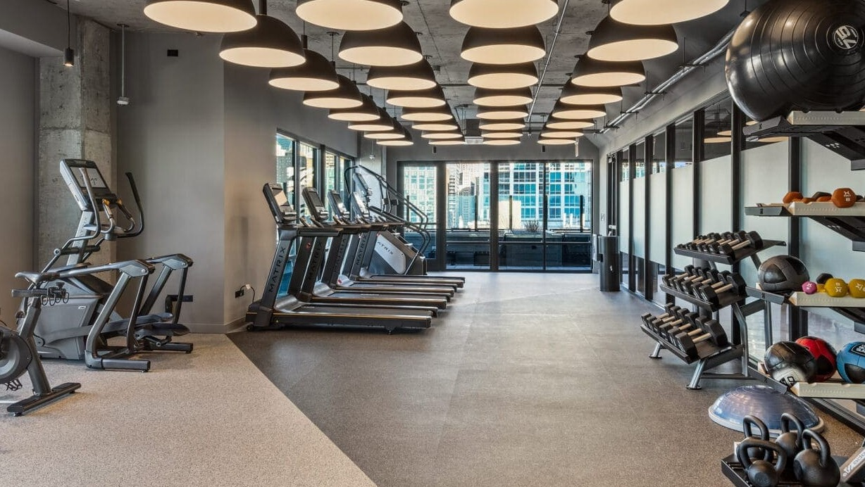Expansive fitness center with a variety of cardio machines, free weights, and modern equipment at Hugo Apartments River North, Chicago